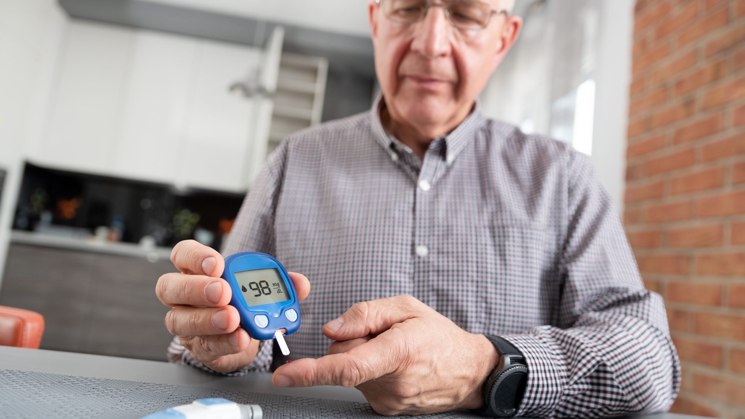 Senior man checking blood sugar level at home