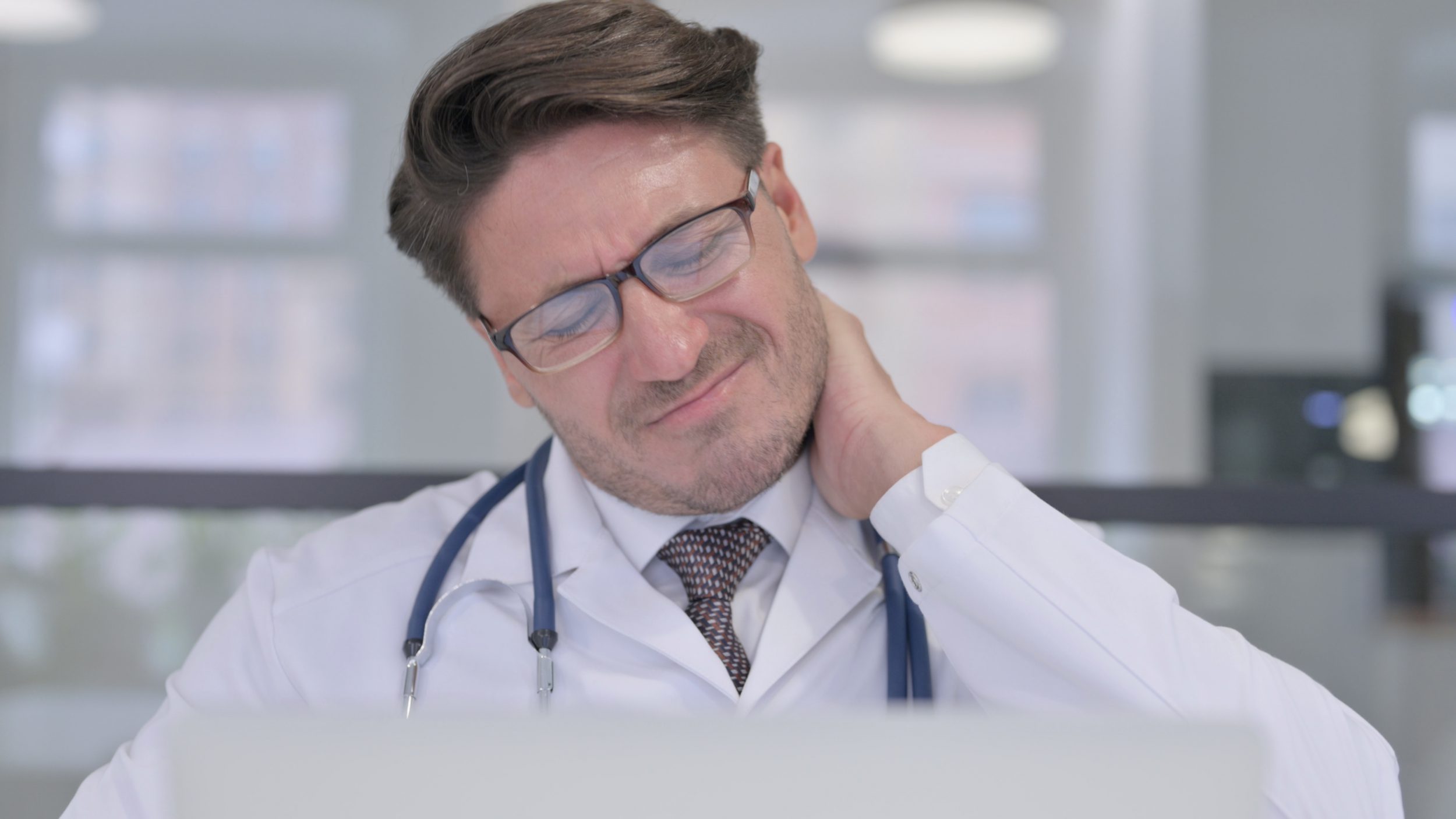 Middle Aged Doctor with Laptop having Neck Pain