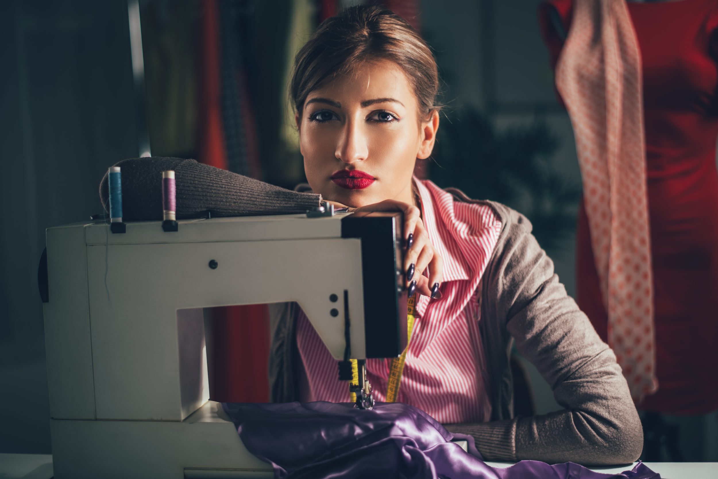 woman sits in front of the sewing machine and thinking.