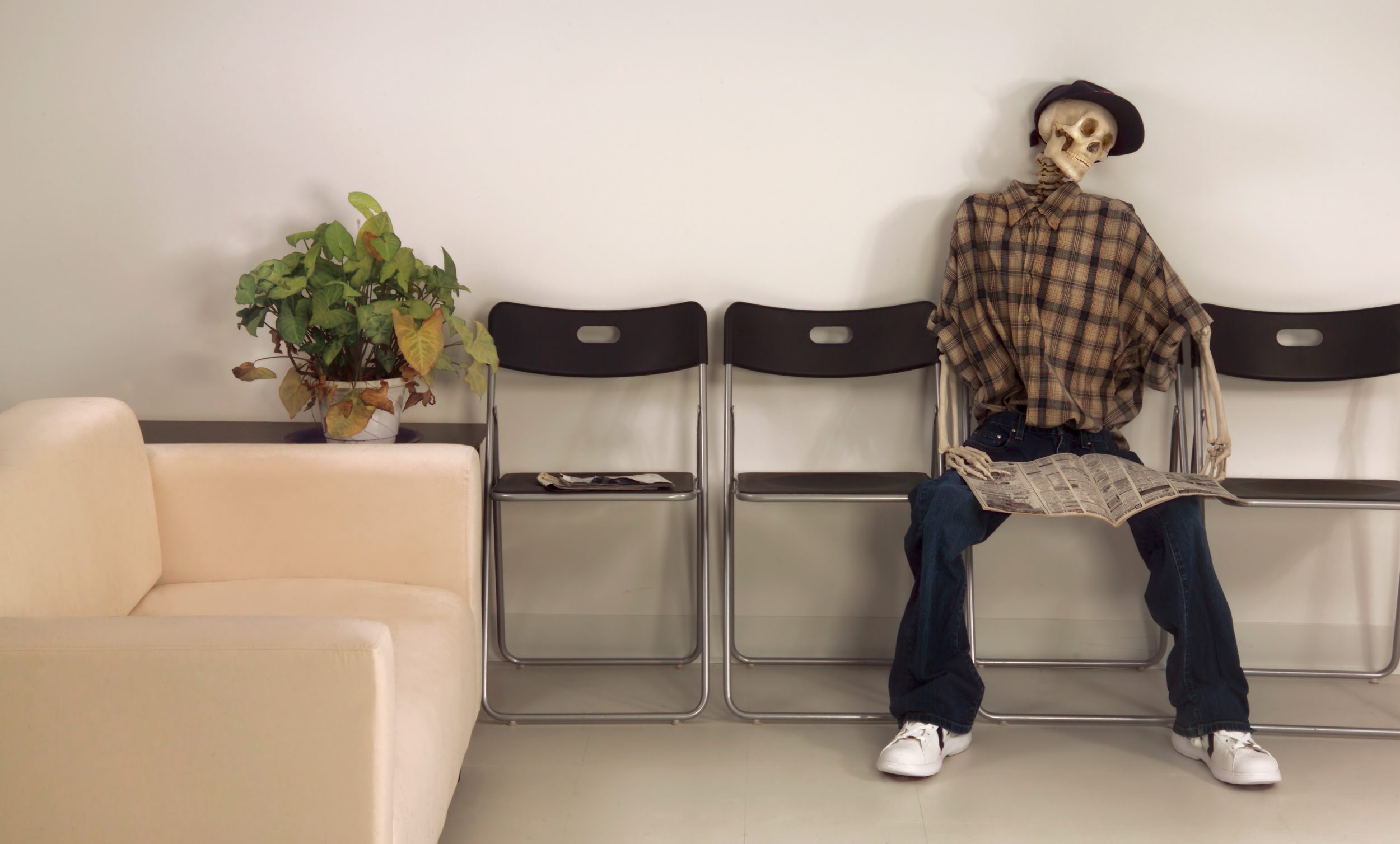 Skeleton Man Sitting Waiting Room with Newspaper