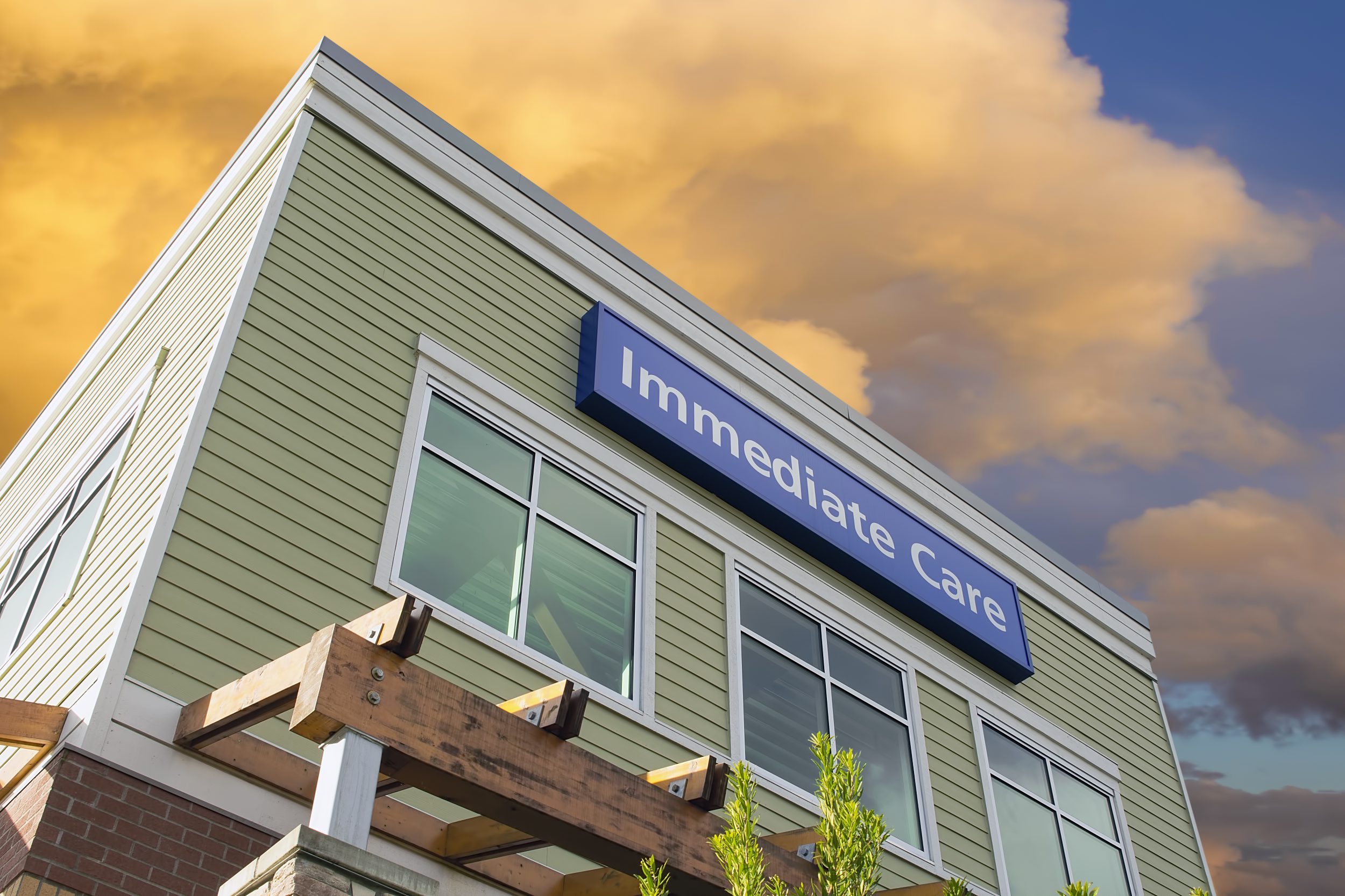 Immediate Care Sign Above Windows Outside Hospital or Emergency Clinic Building Against Sky with Clouds
