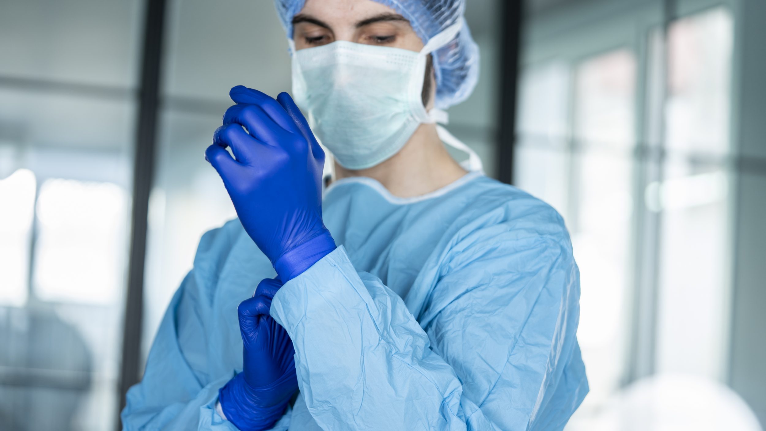 Doctor putting on protective blue gloves from isolation carts