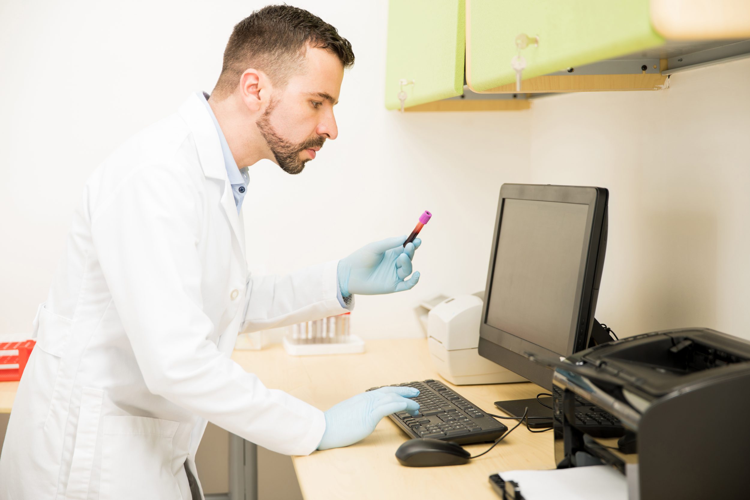 Male doctor adding records of a new blood sample on a medical software database in a lab