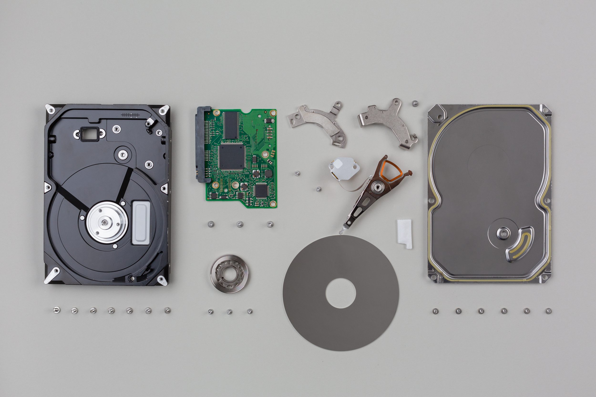 parts of a hard disk belonging to custom medical computer hardware, exploded one by one and arranged on a neutral background